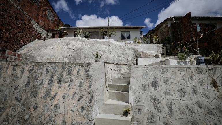 Na diferença de nível entre a rua e a casa o muro de arrimo com pedras